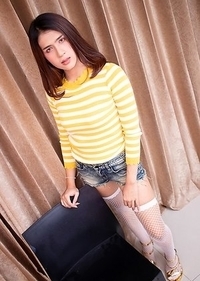 Ladyboy Bipor is wearing a striped yellow sweater with jean booty shorts and high heels.