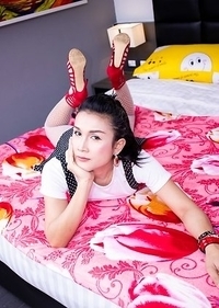 Ladyboy Ice is wearing a skirt with suspender straps over a little white blouse with high heels.