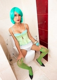Slim Ladyboy Creamy is in the bathroom with wild colored hair and wearing a green blouse and stockings with a white mini skirt.